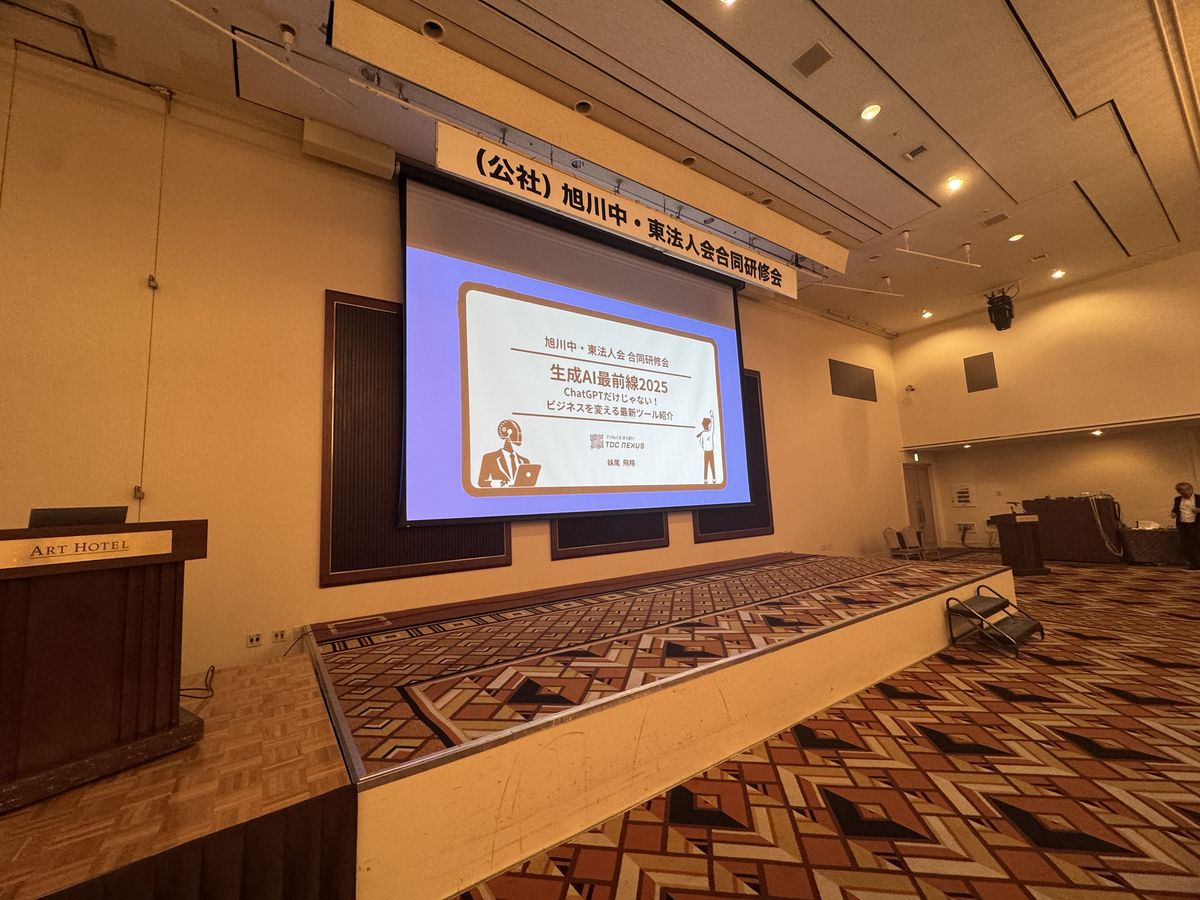 旭川中・東法人会 合同研修会の壇上。スクリーンにTDC NEXUSの生成AIセミナー資料が投影されている